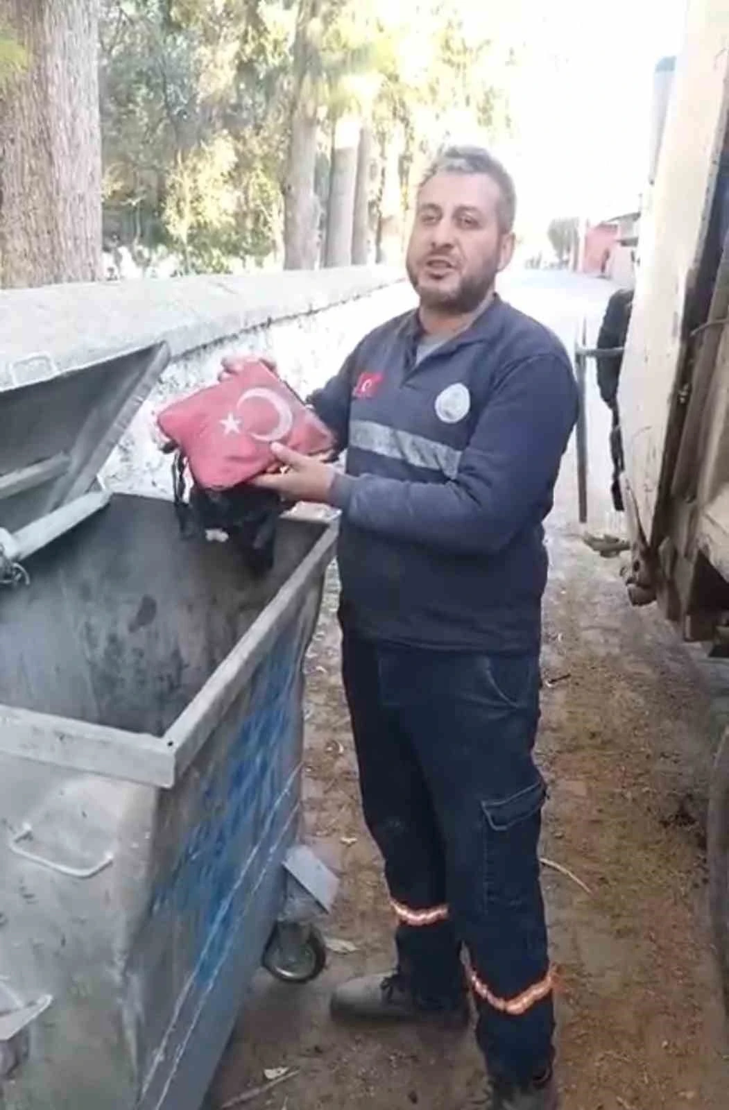 Temizlik işçisi yanmak üzere olan bayrağı çöpten aldı
