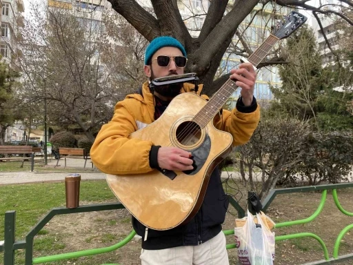 Aynı anda hem mızıka hem de gitar çalıyor
