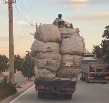 Kamyonetteki yükün üzerindeki çocukların elektrik tellerine çarpmamak için eğilerek gitmeleri kamerada
